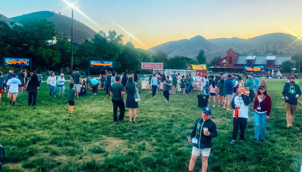 A crowd of people in a grass field at flok Family Camp West in 2023.